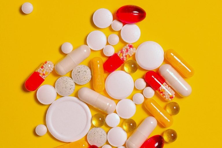 Tablets and capsules on a turmeric yellow background, curcumin vs ibuprofen | Healthcare Discovery