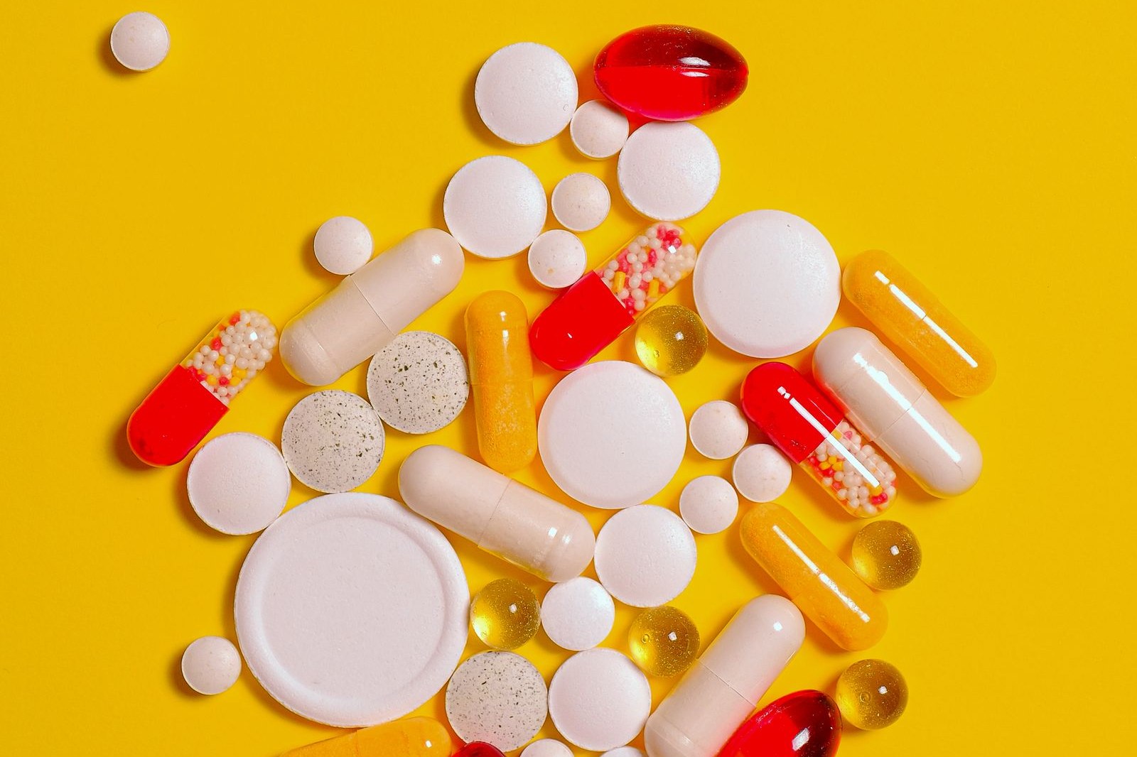 Tablets and capsules on a turmeric yellow background, curcumin vs ibuprofen | Healthcare Discovery
