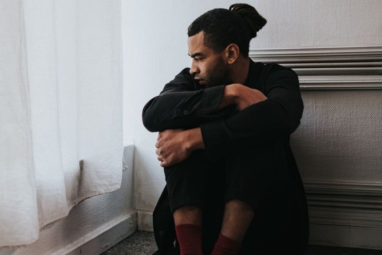 Man sitting alone by a window, curcumin depression research | Healthcare Discovery